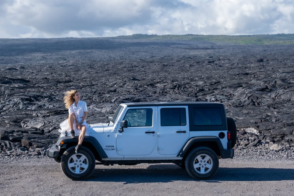 Sylvia Gorajek of America Unlocked on the hood of a white Jeep on a black lava field, on a post about the cost of self-sponsored EB-1A and EB-2 NIW visas