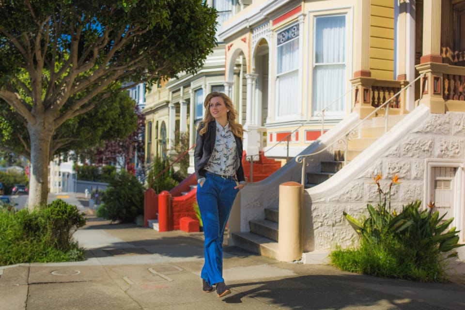 Sylvia Gorajek of America Unlocked walking past colorful Victorian houses in San Francisco, on EB-2 NIW immigration support for AI specialists