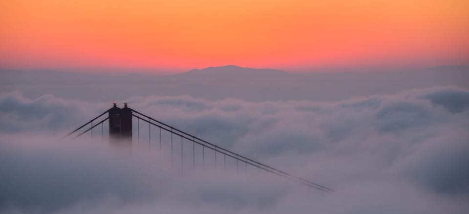 Golden Gate Bridge tower rising above sunrise fog, on the Matter of Dhanasar and EB-2 NIW self-sponsored visa support