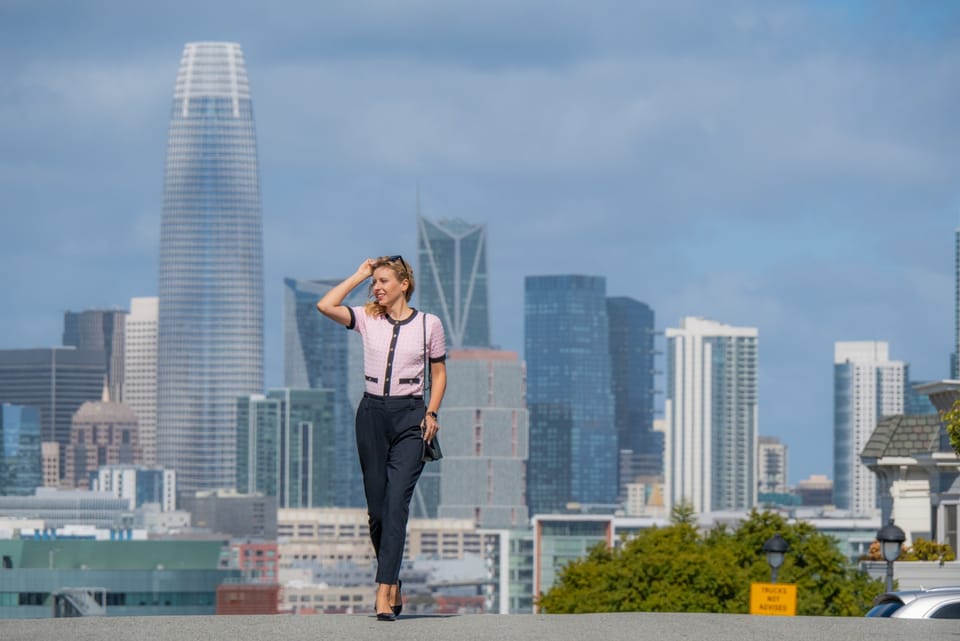 Sylvia Gorajek, founder of America Unlocked, walking a hilltop street with the San Francisco skyline behind her, telling her path from tourist visa to U.S. citizen