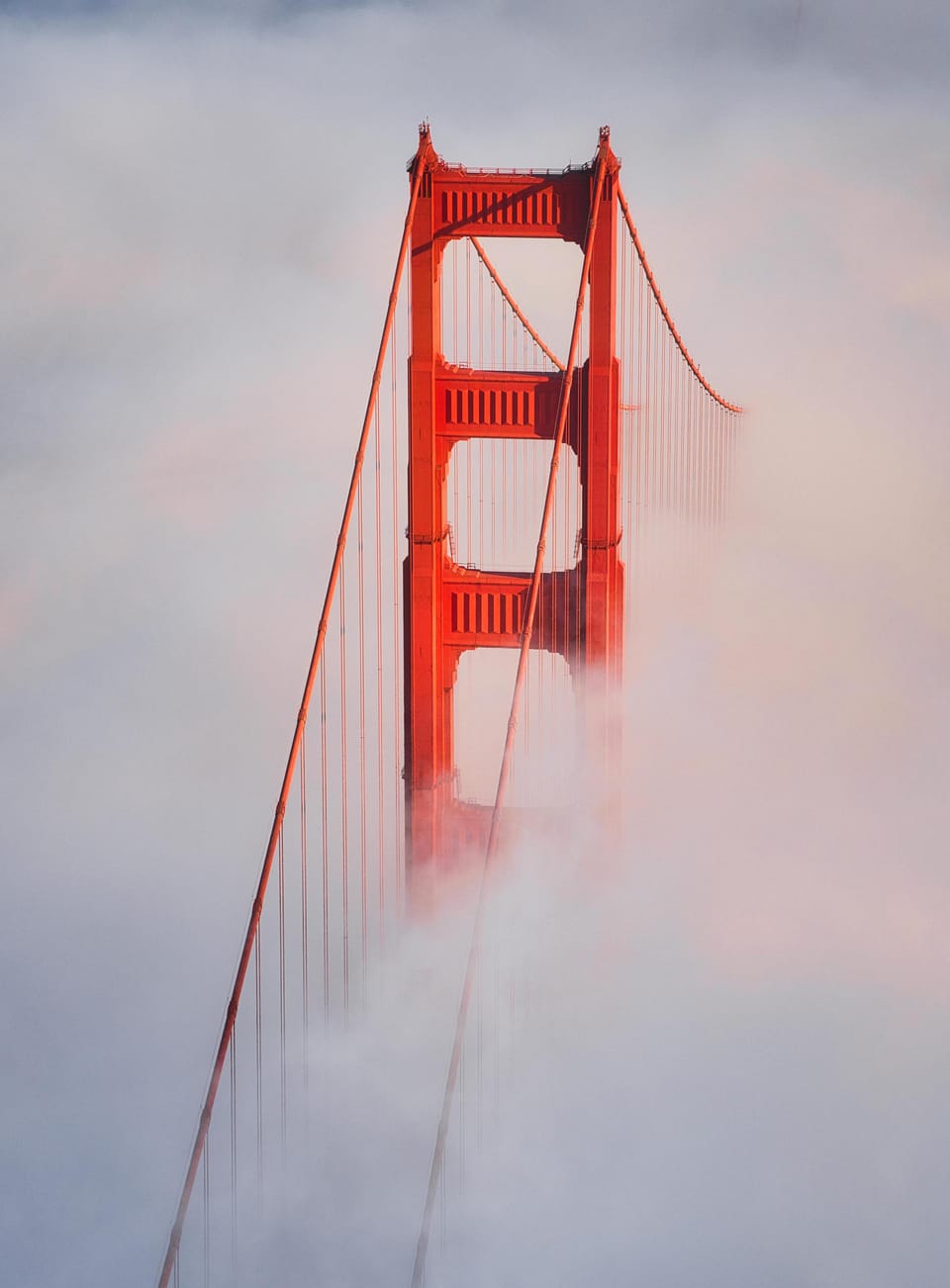 Red towers of the Golden Gate Bridge rising out of thick white fog, on EB-2 NIW requirements and self-sponsored visa support with immigration attorneys